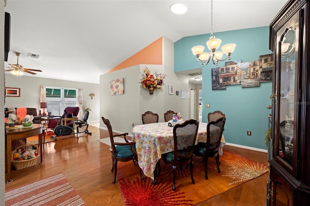 dining space with ceiling fan with notable chandelier, vaulted ceiling, and hardwood / wood-style flooring