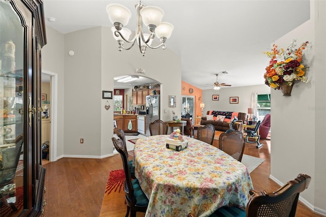 dining space featuring vaulted ceiling, hardwood / wood-style floors, and ceiling fan with notable chandelier