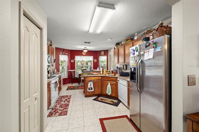 kitchen with kitchen peninsula, stainless steel appliances, sink, pendant lighting, and light tile patterned flooring