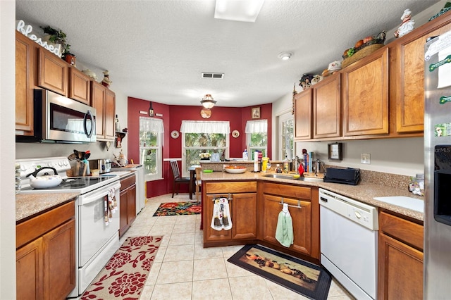 kitchen with appliances with stainless steel finishes, a textured ceiling, light tile patterned floors, and sink