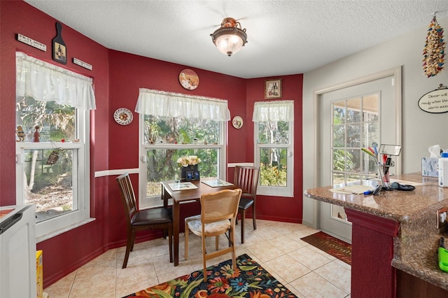 tiled dining room featuring a healthy amount of sunlight and a textured ceiling