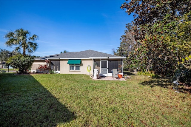 rear view of house featuring a yard and a sunroom