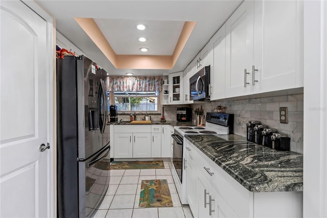 kitchen featuring appliances with stainless steel finishes, tasteful backsplash, a raised ceiling, light tile patterned floors, and white cabinets