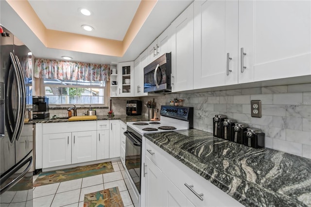 kitchen with black refrigerator with ice dispenser, a raised ceiling, white electric range, sink, and white cabinetry