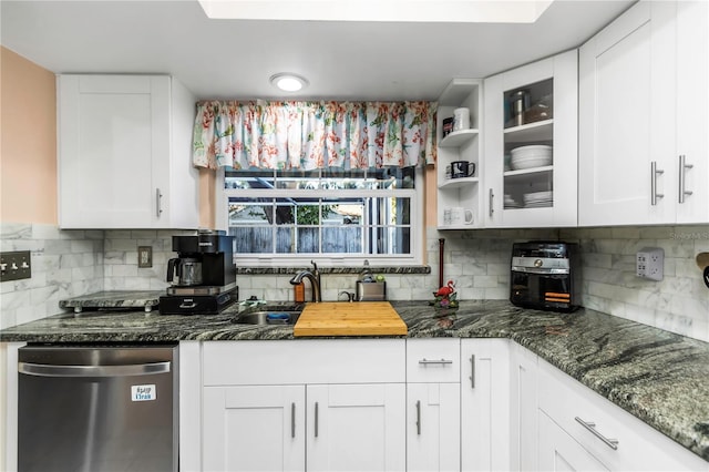 kitchen featuring white cabinets, decorative backsplash, stainless steel dishwasher, and dark stone counters