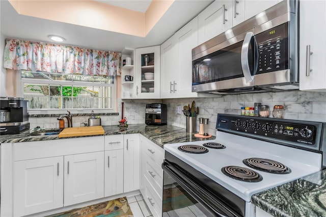 kitchen with electric range, white cabinetry, dark stone counters, and backsplash