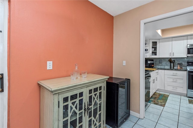 kitchen featuring backsplash, wine cooler, range with electric stovetop, light tile patterned floors, and white cabinetry