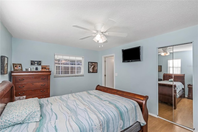 bedroom with a textured ceiling, light wood-type flooring, a closet, and ceiling fan