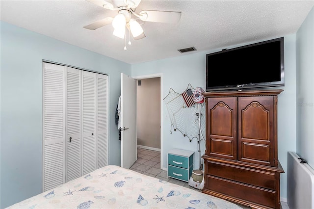 tiled bedroom with ceiling fan, a textured ceiling, and a closet