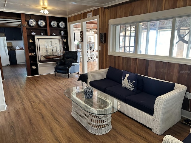 living room with built in features, wood-type flooring, and ornamental molding