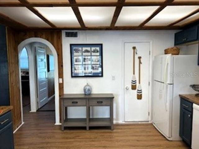 kitchen with blue cabinetry, white fridge, wood-type flooring, and coffered ceiling