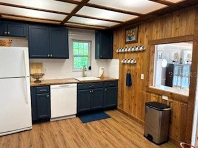 kitchen featuring wood walls, sink, white appliances, and blue cabinets