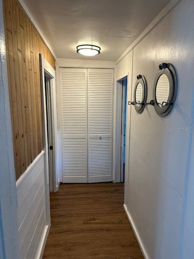 hallway with dark hardwood / wood-style flooring, wooden walls, and crown molding