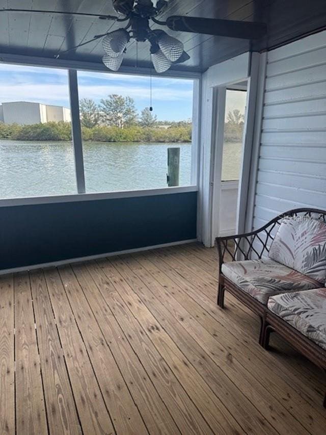 unfurnished sunroom featuring a water view and ceiling fan