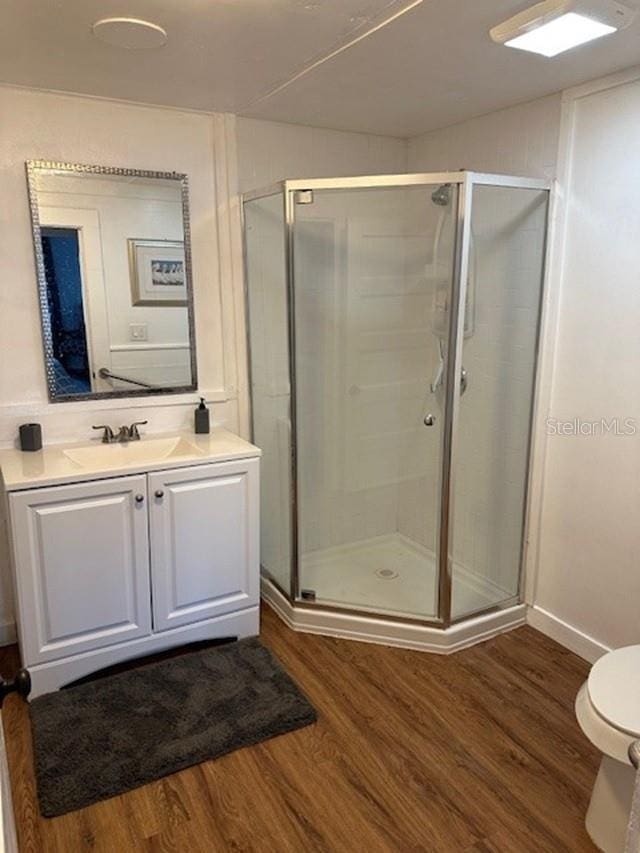 bathroom featuring hardwood / wood-style floors, vanity, toilet, and walk in shower