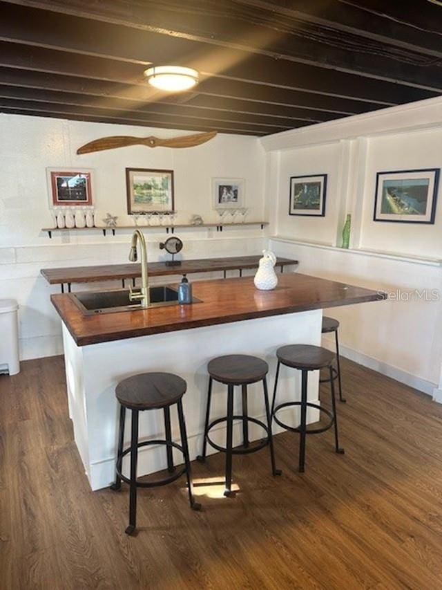 kitchen with butcher block counters, sink, beamed ceiling, and dark hardwood / wood-style flooring