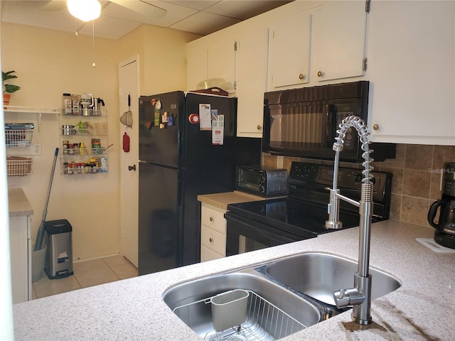 kitchen with tasteful backsplash, sink, black appliances, light tile patterned floors, and white cabinetry