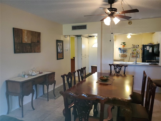 tiled dining area with ceiling fan and a textured ceiling