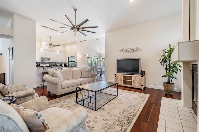 living room with hardwood / wood-style floors, high vaulted ceiling, and ceiling fan