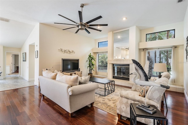 living room with a fireplace, wood-type flooring, a wealth of natural light, and ceiling fan