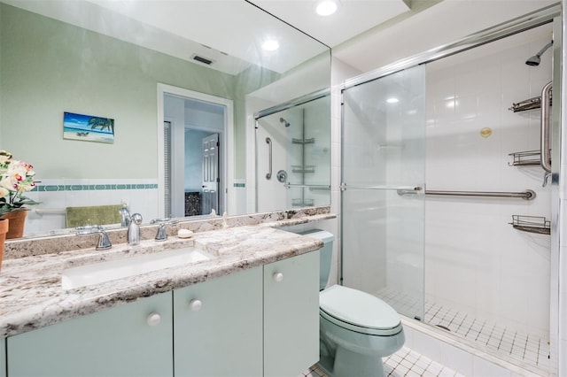 bathroom featuring tile patterned floors, vanity, toilet, and a shower with door