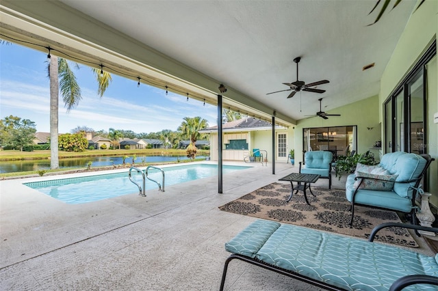 view of pool with an outdoor living space, a water view, ceiling fan, and a patio area