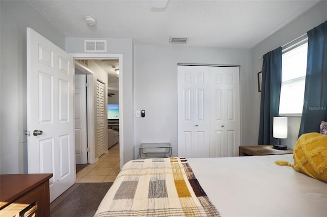 bedroom featuring light tile patterned flooring, a closet, and a textured ceiling