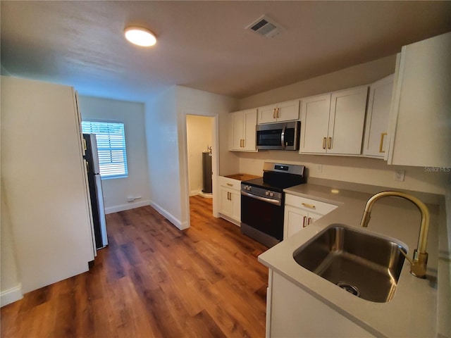 kitchen with white cabinets, appliances with stainless steel finishes, dark wood-type flooring, and sink