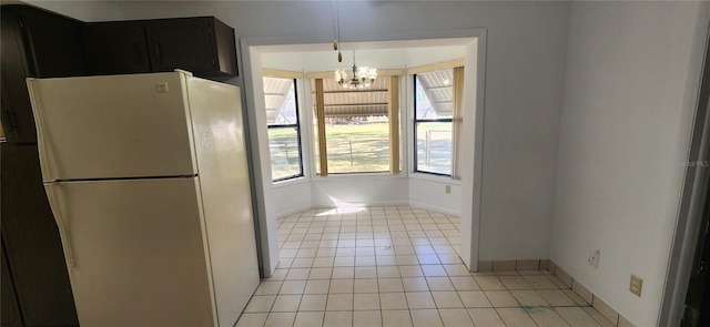 kitchen with white refrigerator, light tile patterned flooring, pendant lighting, and a chandelier