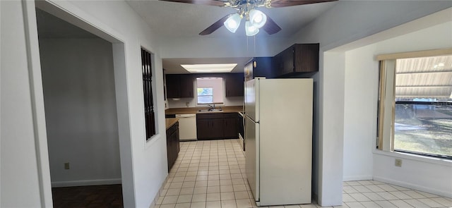 kitchen featuring sink, light tile patterned floors, dark brown cabinetry, ceiling fan, and white appliances