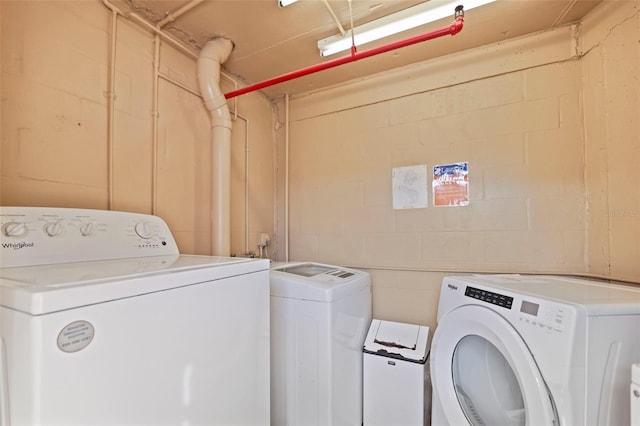 laundry room featuring concrete block wall and washer and clothes dryer