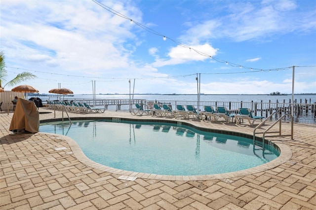 community pool with a water view, fence, and a patio