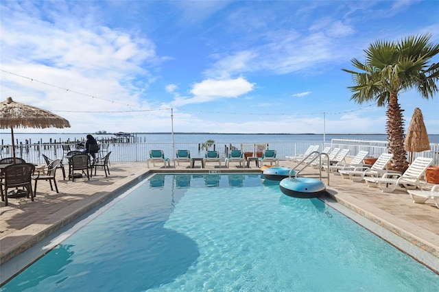 pool featuring a water view, a patio, and fence