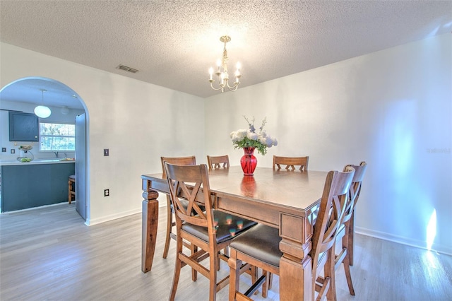 dining room with hardwood / wood-style floors, a textured ceiling, and a notable chandelier