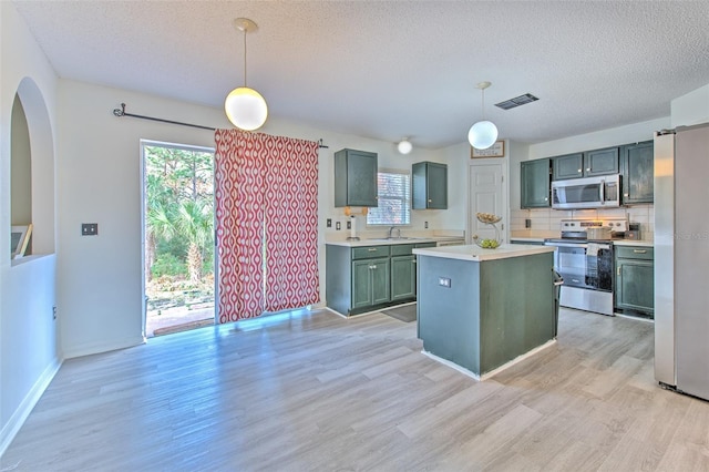 kitchen featuring sink, hanging light fixtures, a center island, stainless steel appliances, and light hardwood / wood-style flooring