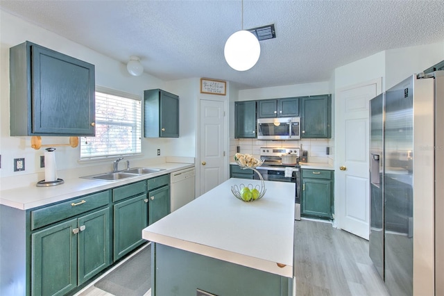 kitchen with sink, hanging light fixtures, a center island, light hardwood / wood-style floors, and stainless steel appliances