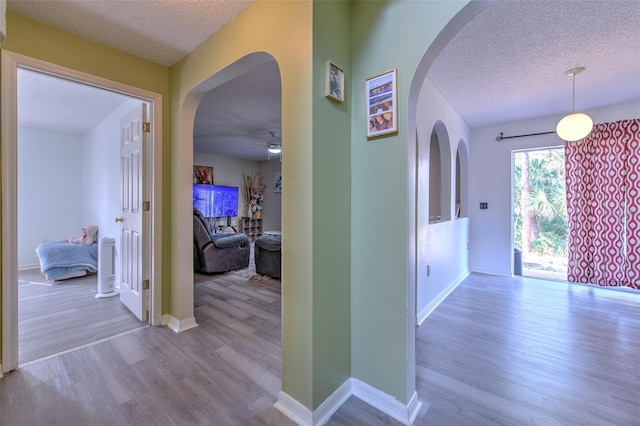 hallway featuring light hardwood / wood-style floors and a textured ceiling