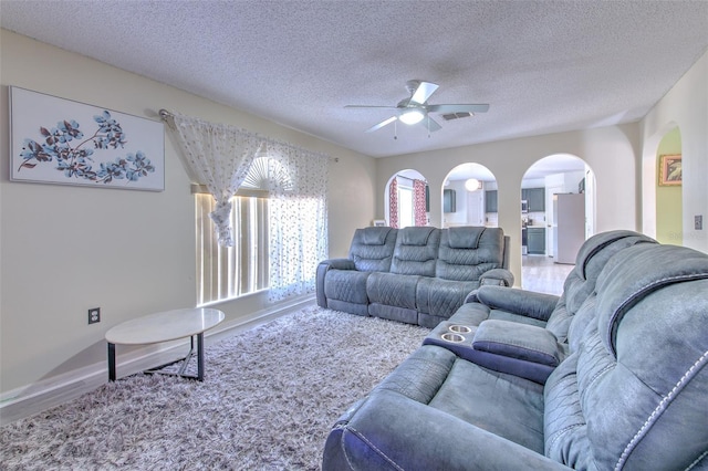 living room featuring ceiling fan, hardwood / wood-style floors, and a textured ceiling