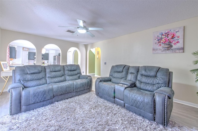 living room with hardwood / wood-style flooring, ceiling fan, and a textured ceiling