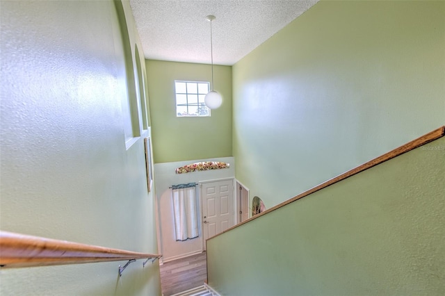 stairway featuring hardwood / wood-style flooring and a textured ceiling