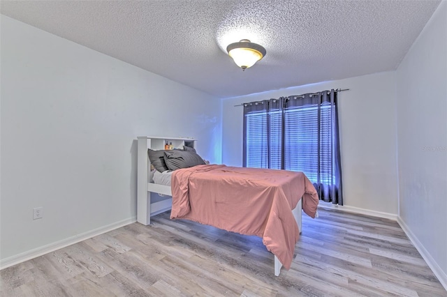 bedroom with a textured ceiling and light wood-type flooring