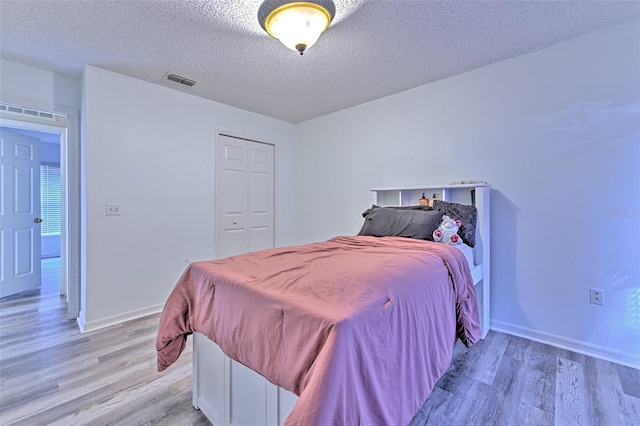 bedroom with a closet, a textured ceiling, and light wood-type flooring