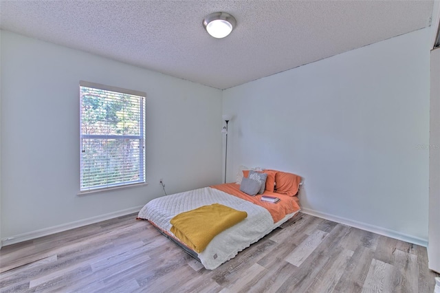 bedroom with a textured ceiling and light wood-type flooring