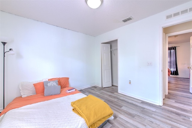 bedroom featuring a textured ceiling and light hardwood / wood-style flooring