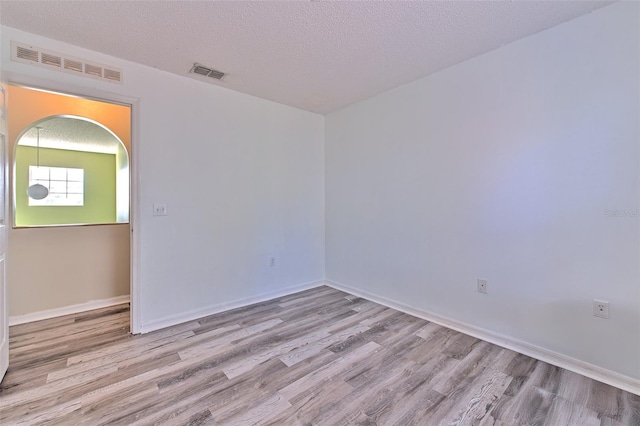 spare room with light hardwood / wood-style floors and a textured ceiling