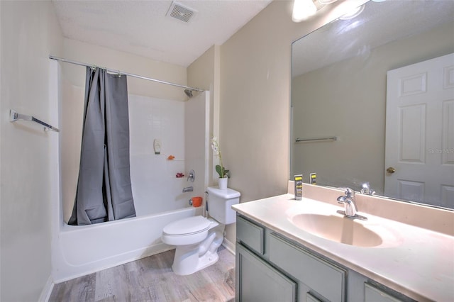 full bathroom featuring shower / bathtub combination with curtain, hardwood / wood-style flooring, vanity, a textured ceiling, and toilet