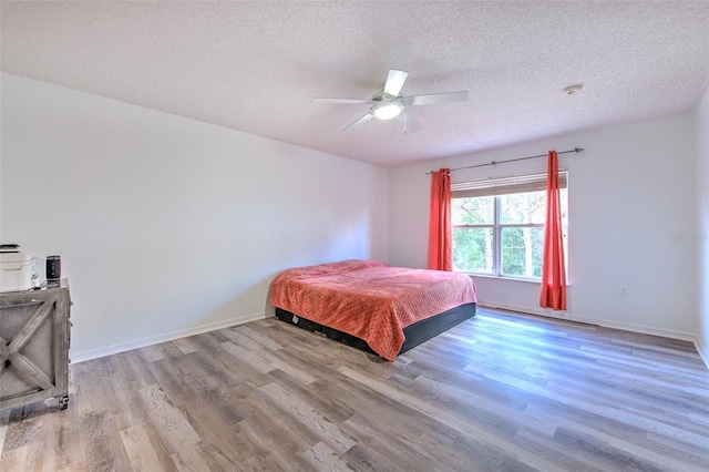 bedroom with ceiling fan, a textured ceiling, and light hardwood / wood-style flooring