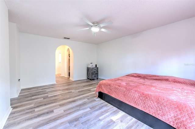 bedroom featuring ceiling fan, a textured ceiling, and light wood-type flooring