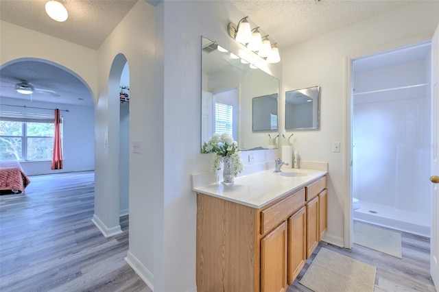 bathroom featuring ceiling fan, vanity, hardwood / wood-style floors, and a textured ceiling