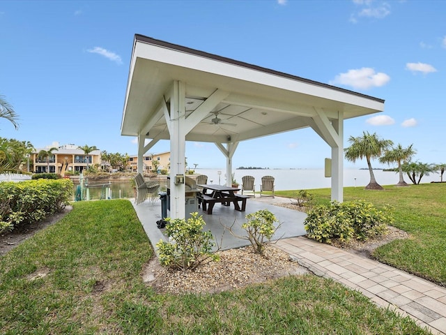 view of community with a patio area, a yard, and a water view